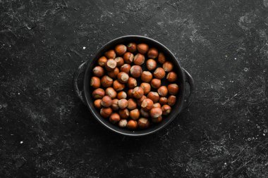 Siyah taşlı arka planda bir kasede fındık. Çatlak. Metnin için boş yer. Üst görünüm.