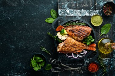 Siyah taş bir tabakta sebzeli fırında kırmızı balık levreği. Üst Manzara. Metnin için boş yer.