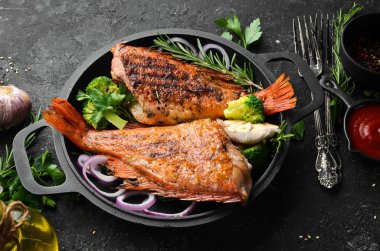 Siyah taş bir tabakta sebzeli fırında kırmızı balık levreği. Üst Manzara. Metnin için boş yer.