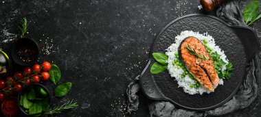 Siyah taş tabakta pilav ve sebzeli somon bifteği. Deniz ürünleri. Üst Manzara. Metnin için boş yer.