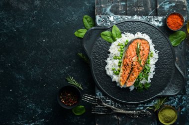 Siyah taş tabakta pilav ve sebzeli somon bifteği. Deniz ürünleri. Üst Manzara. Metnin için boş yer.
