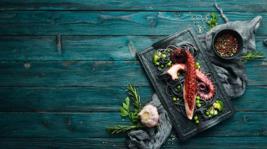 Siyah taş tabakta ahtapot dokunaçlı siyah makarna. Deniz ürünleri. Üst Manzara. Metnin için boş yer.