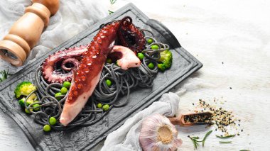 Siyah taş tabakta ahtapot dokunaçlı siyah makarna. Deniz ürünleri. Üst Manzara. Metnin için boş yer.