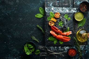 Siyah taş tabakta siyah makarna ve sebzeli ıstakoz pençesi. Deniz ürünleri. Üst Manzara. Metnin için boş yer.