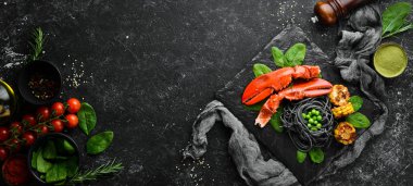 Siyah taş tabakta siyah makarna ve sebzeli ıstakoz pençesi. Deniz ürünleri. Üst Manzara. Metnin için boş yer.