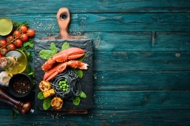 Siyah taş tabakta siyah makarna ve sebzeli ıstakoz pençesi. Deniz ürünleri. Üst Manzara. Metnin için boş yer.