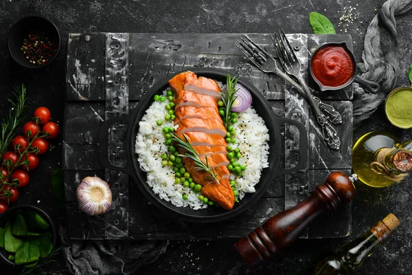 Baked chicken fillet with rice and vegetables on a black stone plate. Diet food. Top view. Free space for your text.