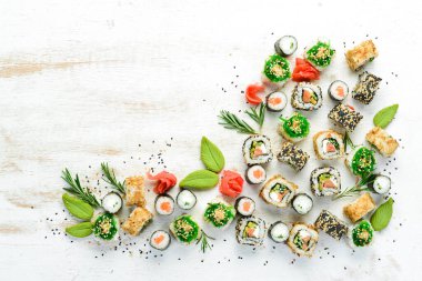 Beyaz ahşap arka planda lezzetli suşi ve maki ruloları. Japon yemeği. Üst Manzara. Metnin için boş yer.