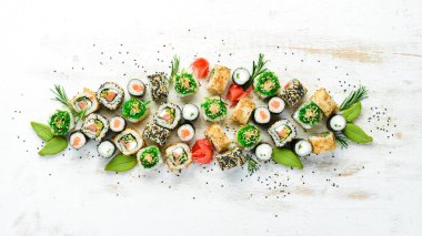 Beyaz ahşap arka planda lezzetli suşi ve maki ruloları. Japon yemeği. Üst Manzara. Metnin için boş yer.