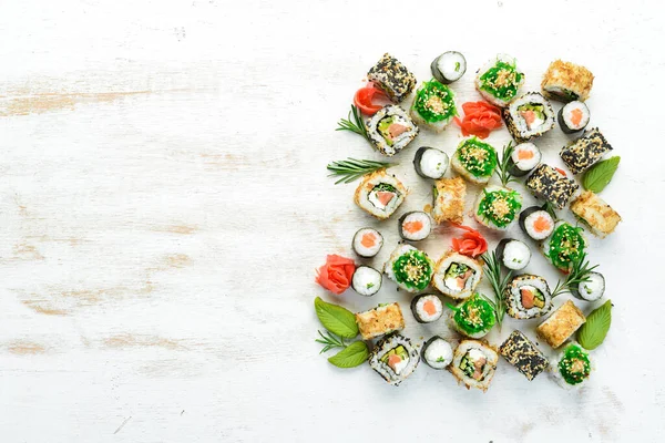 Beyaz ahşap arka planda lezzetli suşi ve maki ruloları. Japon yemeği. Üst Manzara. Metnin için boş yer.