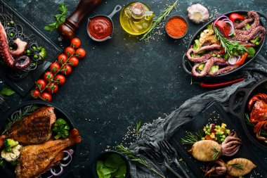 Deniz ürünleri tabakları. Siyah taş zemin üzerinde balık, mürekkep balığı, ahtapot. Üst Manzara. Metnin için boş yer.