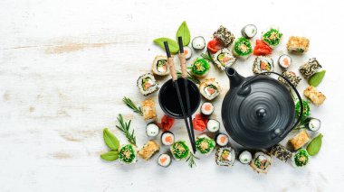Suşi ruloları ve beyaz ahşap arka planda çay ile çaydanlık. Harika Japon yemekleri..