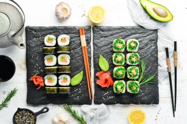 Siyah tabakta geleneksel suşi seti. Suşi ve rulo beyaz ahşap arka planda.