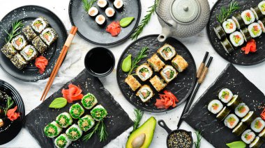 Siyah tabakta geleneksel suşi seti. Suşi ve rulo beyaz ahşap arka planda.