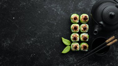 Yeşil suşi rulo - yılan balığı ve yeşil Tobiko havyarlı. Lezzetli suşi parçaları. Üst görünüm.