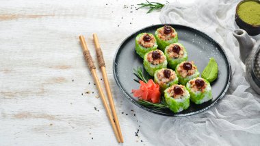 Yeşil suşi rulo - yılan balığı ve yeşil Tobiko havyarlı. Lezzetli suşi parçaları. Üst görünüm.