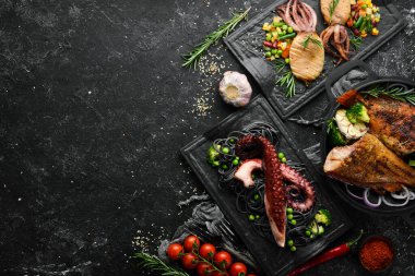 Deniz ürünleri tabakları. Siyah taş zemin üzerinde balık, mürekkep balığı, ahtapot. Üst Manzara. Metnin için boş yer.