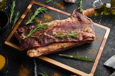 Biberiye ve baharatlı kurutulmuş tuzlu et. Jamon. Siyah taştan bir arka planda. Üst görünüm.