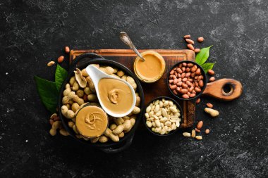 Siyah taşlı arka planda fıstık ezmesi ve fıstık. Sağlıklı yiyecekler. Üst görünüm.