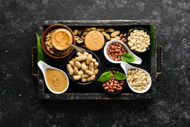 Siyah taşlı arka planda fıstık ezmesi ve fıstık. Sağlıklı yiyecekler. Üst görünüm.