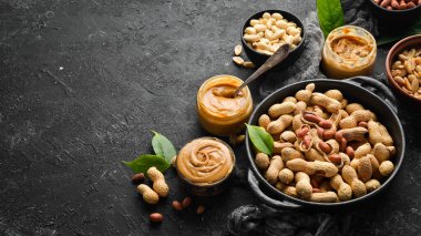 Siyah taşlı arka planda fıstık ezmesi ve fıstık. Sağlıklı yiyecekler. Üst görünüm.