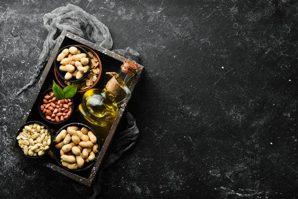 Peanut oil is cold pressed. Peanuts on a black stone background. Top view