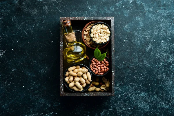 Peanut oil is cold pressed. Peanuts on a black stone background. Top view