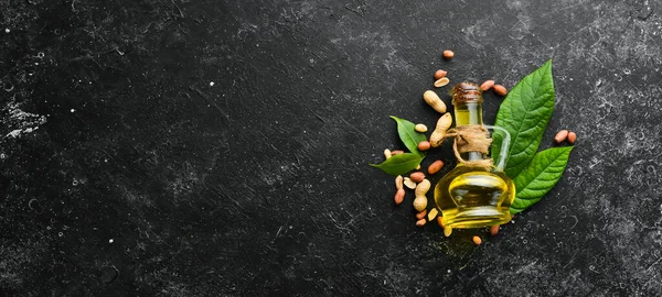 Peanut oil is cold pressed. Peanuts on a black stone background. Top view