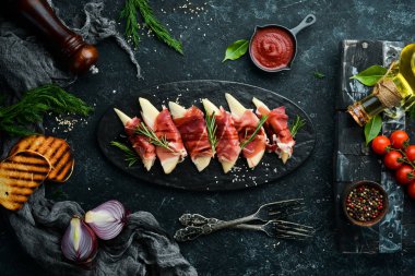 İtalyan yemeği. Armut ve balzamik soslu jambon. Jamon siyah taştan bir tabakta. Üst görünüm.