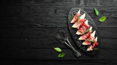 İtalyan yemeği. Armut ve balzamik soslu jambon. Jamon siyah taştan bir tabakta. Üst görünüm.