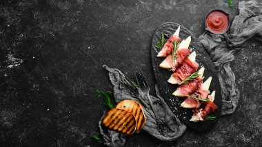 İtalyan yemeği. Armut ve balzamik soslu jambon. Jamon siyah taştan bir tabakta. Üst görünüm.