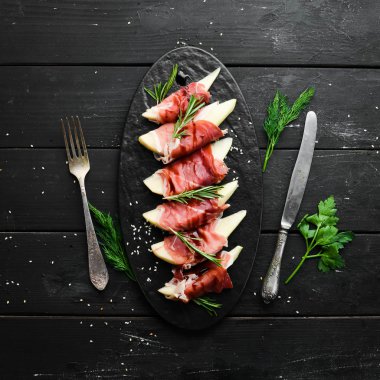 İtalyan yemeği. Armut ve balzamik soslu jambon. Jamon siyah taştan bir tabakta. Üst görünüm.