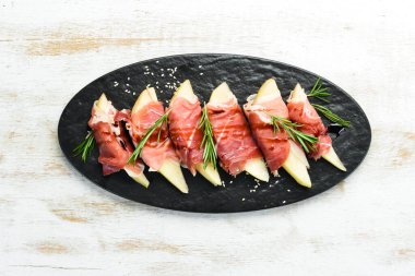 İtalyan yemeği. Armut ve balzamik soslu jambon. Jamon siyah taştan bir tabakta. Üst görünüm.