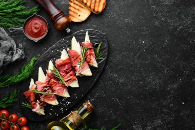 İtalyan yemeği. Armut ve balzamik soslu jambon. Jamon siyah taştan bir tabakta. Üst görünüm.