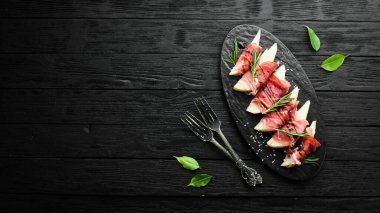 İtalyan yemeği. Armut ve balzamik soslu jambon. Jamon siyah taştan bir tabakta. Üst görünüm.