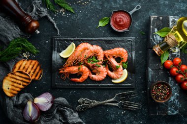 Siyah taş tabakta maydanozlu ve limonlu haşlanmış karides. Üst Manzara. Deniz ürünleri..