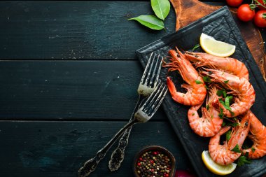 Siyah taş tabakta maydanozlu ve limonlu haşlanmış karides. Üst Manzara. Deniz ürünleri..