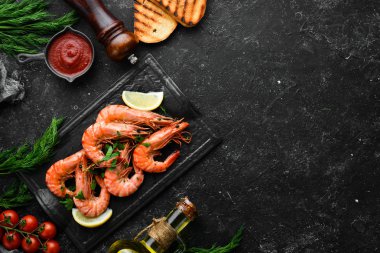 Siyah taş tabakta maydanozlu ve limonlu haşlanmış karides. Üst Manzara. Deniz ürünleri..