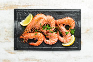 Siyah taş tabakta maydanozlu ve limonlu haşlanmış karides. Üst Manzara. Deniz ürünleri..