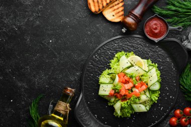 Salatalı salata, somon ve marul. Sağlıklı yiyecekler. Siyah taştan bir tabakta. Üst görünüm.