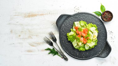 Salatalı salata, somon ve marul. Sağlıklı yiyecekler. Siyah taştan bir tabakta. Üst görünüm.