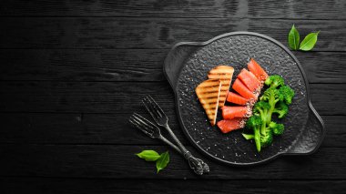 Brokoli ve tuzlanmış somon balığı. Sağlıklı Diyet Yemekleri. Siyah taştan bir tabakta. Üst görünüm.