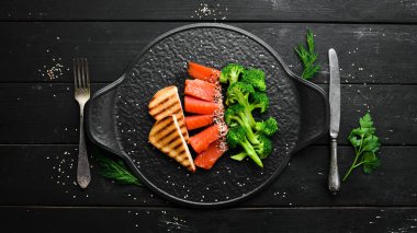 Brokoli ve tuzlanmış somon balığı. Sağlıklı Diyet Yemekleri. Siyah taştan bir tabakta. Üst görünüm.