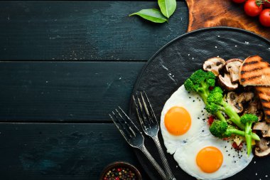 Sağlıklı kahvaltı. Brokolili yumurta, mantar ve ekmek. Siyah taştan bir tabakta. Üst görünüm.