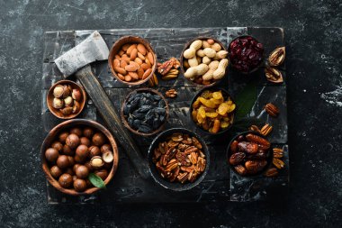 Siyah bir arka planda fındık ve kurutulmuş meyve ve dut seti. Üst Manzara. Metnin için boş yer.