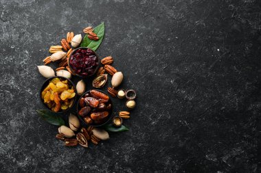 Siyah bir arka planda fındık ve kurutulmuş meyve ve dut seti. Üst Manzara. Metnin için boş yer.