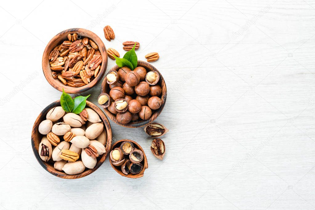 Set of nuts. pecans and macadamia nuts in bowls on a white background. Top view. Free space for your text.