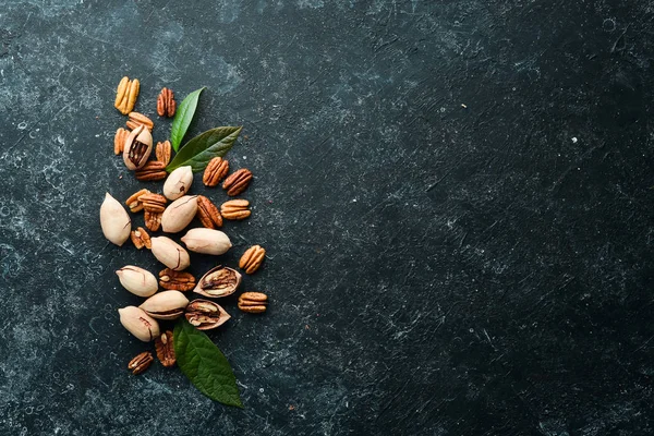 Pecan nut on black stone background. Assortment of pecans. Top preview. Free space for your text.