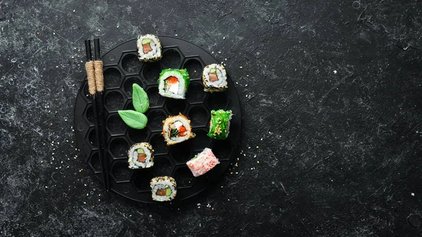 Siyah taşlı arka planda deniz mahsulleri olan büyük bir suşi sarması. Üst Manzara. Metnin için boş yer.