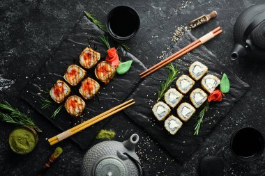 Suşi bar menüsü. Siyah tabakta renkli lezzetli suşi ruloları. Üst görünüm.